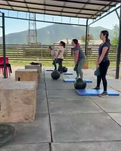 Clase de Funcional en el box: alumnas con balones medicinales entre cajones, con los cerros de fondo